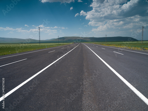 Straight asphalt road between fields