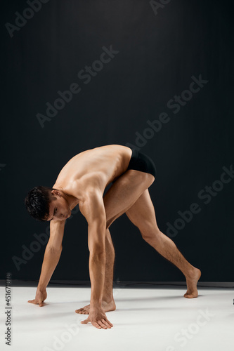 bodybuilder with muscular body in black shorts posing dark background