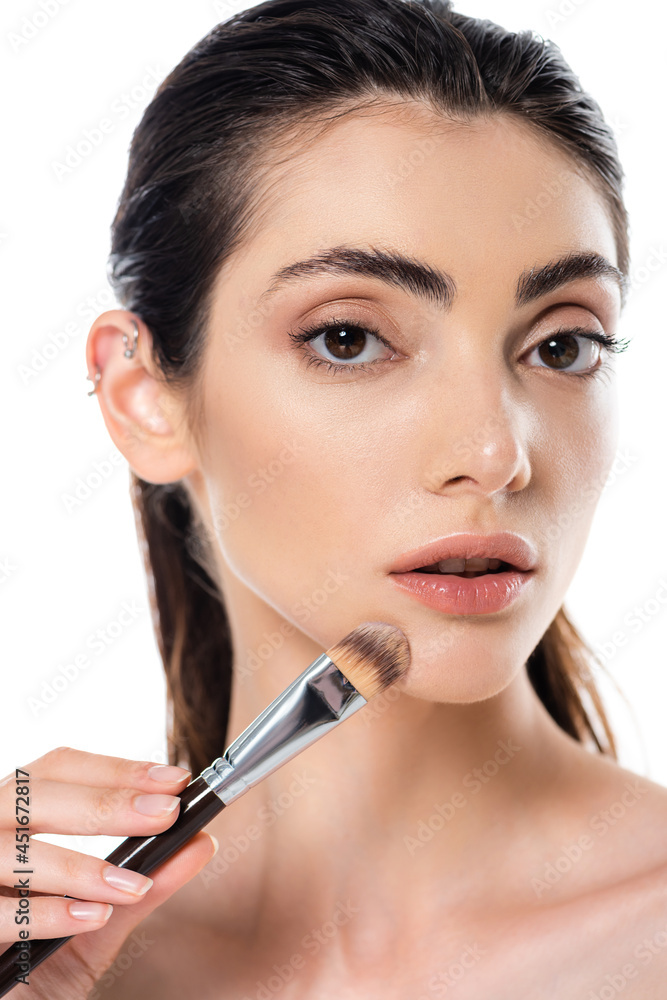 young woman applying face foundation with cosmetic brush isolated on white young woman applying face foundation with cosmetic brush isolated on white