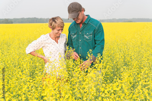 man and woman standing in a canola field