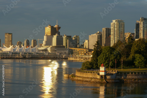 Vancouver cityscape at early morning hour. Brockton Point Lighthouse in the foreground, Canada Place and skyscrapers in the background, sunlight (sunbeam) across the water. Vancouver, Canada. photo