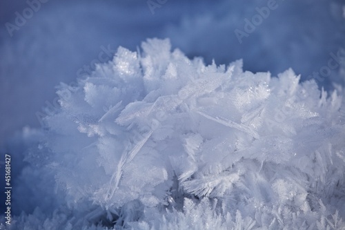 White ice crystals in bright sunlight. Macro photography of ice crystal texture. Snow crystals close-up on a bright frosty winter day. White sparkling snow surface close up. Abstract snowy pattern.