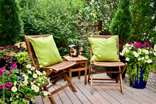 Secluded outdoor oasis at summer Airbnb vacation rental, relaxation in small backyard landscaped garden. Luxury lifestyle relaxing with chilled glass of wine in outdoor cafe seating.