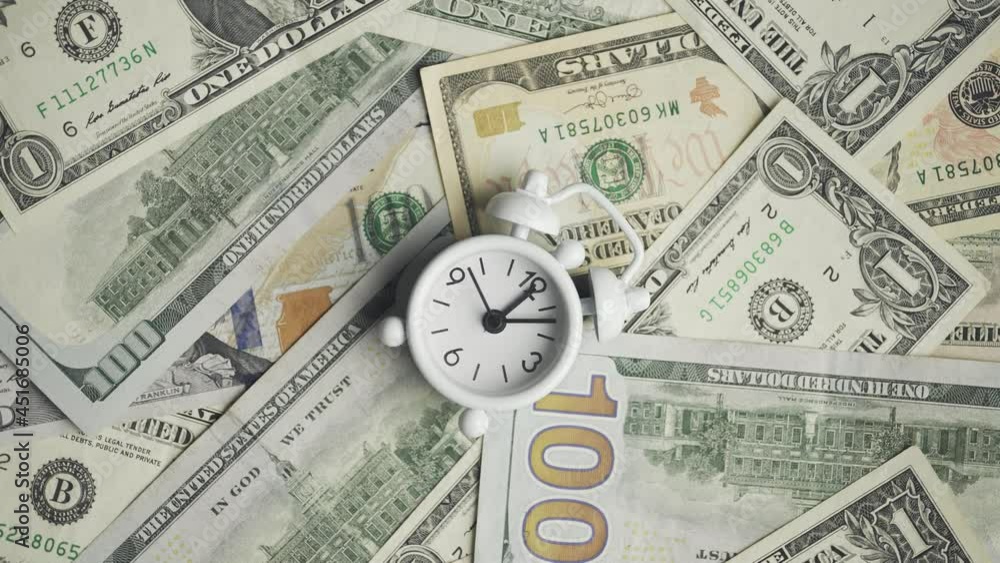 Time is money. Rotation of a clock lying on the dollar bills. Expenses and incomes. Finance or savings and accounting. Concept of counting budget and taxes or payments and wage. Close up. 4k footage Time is money. Rotation of a clock lying on the dollar bills. Expenses and incomes. Finance or savings and accounting. Concept of counting budget and taxes or payments and wage. Close up. 4k footage