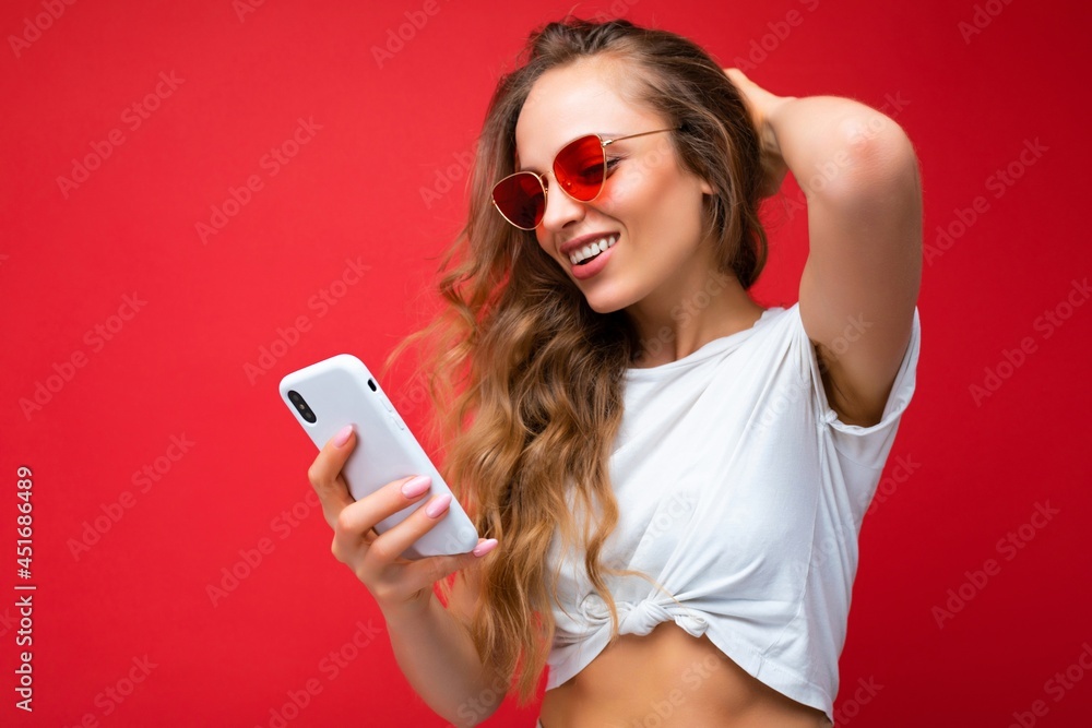 Beautiful young woman wearing casual clothes standing isolated over background surfing on the internet via phone looking at mobile screen