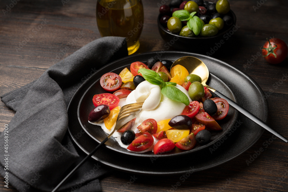 Typical food of the Italian region of Apulia burrata cheese with tomatoes and basil. Italy food. Caprese salad with tomatoes and mozzarella. 