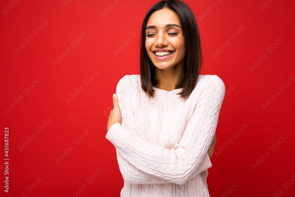 Portrait of positive cheerful cute smiling young brunette woman in casual sweater isolated on red background with copy space Portrait of positive cheerful cute smiling young brunette woman in casual sweater isolated on red background with copy space