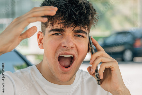 portrait teenage boy screaming with mobile phone