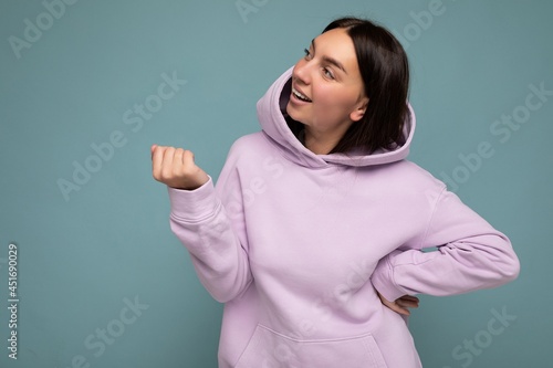 Shot of attractive happy smiling young woman wearing casual outfit standing isolated over colourful background with empty space looking to the side