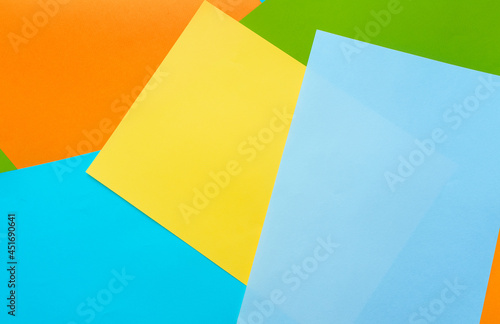 A five sheets of colored paper (blue, turquoise, yellow, green, orange) are mixed. Design cardboard background, copy space.