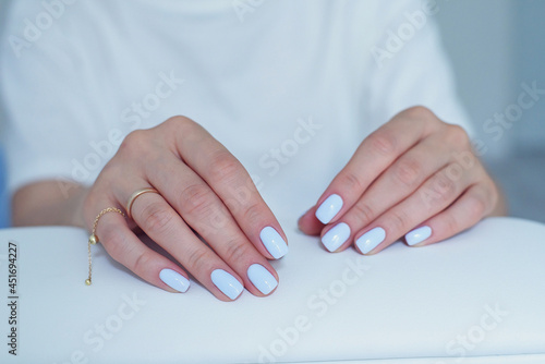 Beautiful female hands with a gentle blue manicure on a stand at beauty salon.