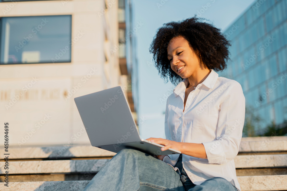 A woman smiles afrovneshnost student communicates on a social network with friends. A freelancer uses a laptop for online training. A woman smiles afrovneshnost student communicates on a social network with friends. A freelancer uses a laptop for online training.