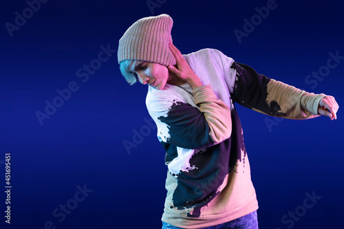 Fototapeta Naklejka Na Ścianę i Meble -  Latin woman dancing choreography in studio with casual clothes and blue background with purple