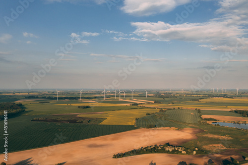 Drone photography of the wind turbine farm on the green fields of Poland during late early summer. Sustainable energy generation from the wind turbines.