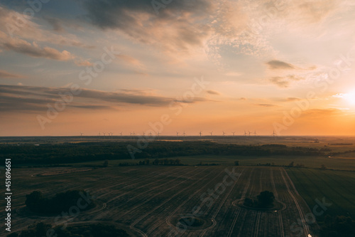 Drone photography of the wind turbine farm on the green fields of Poland during late early summer. Sustainable energy generation from the wind turbines. © marcinjozwiak