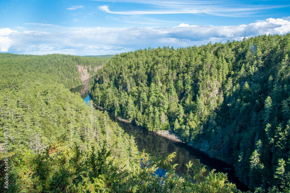 The Barron River cuts through the lush green forested canyon in eastern Algonquin Park, Ontario, on a bright sunny day.