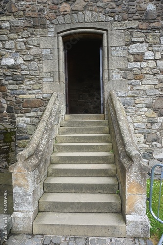 Steps leading up to a dark doorway in the exterior wall of an ancient stone building
