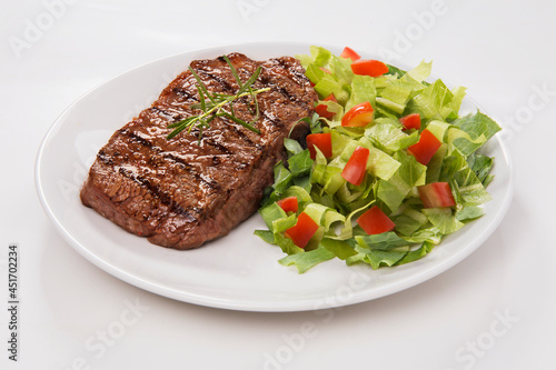 Delicioso corte de carne bovina grelhada com salada de alface picada com tomate e pepino. No fundo branco para recorte. photo