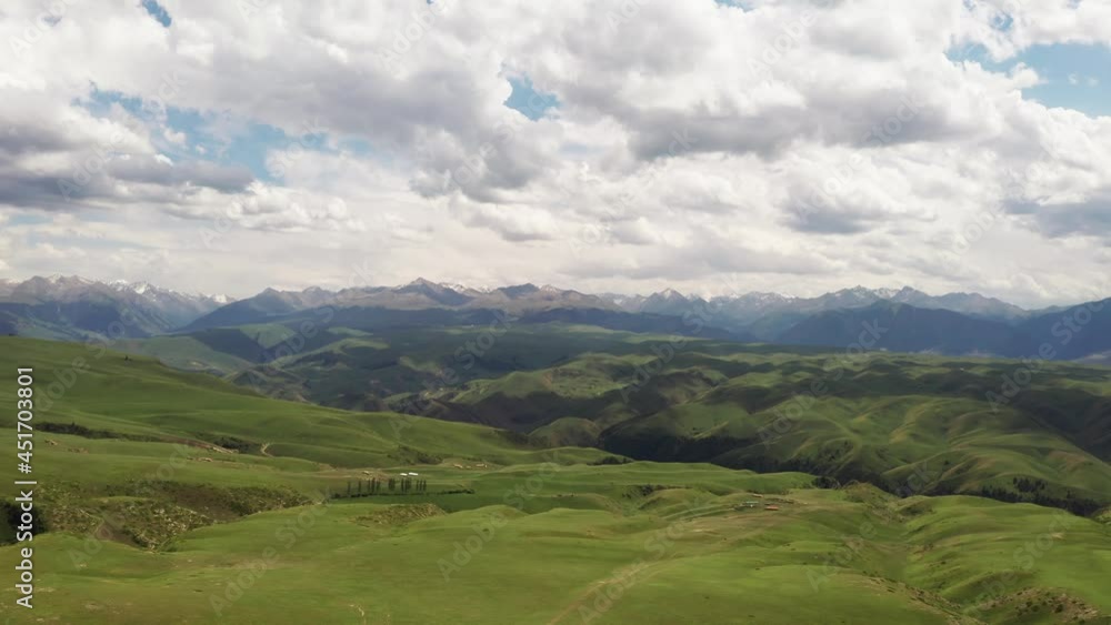 Mountain peaks and grassland are under white clouds. Mountain peaks and grassland are under white clouds.