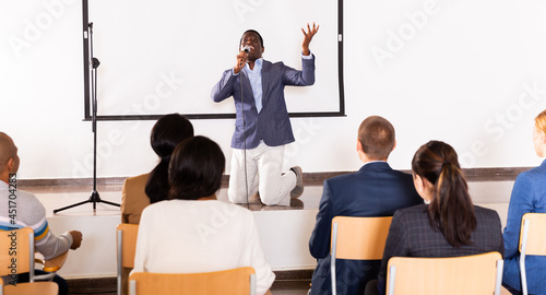 Portrait of cheerful successful man giving motivation training at conference hall