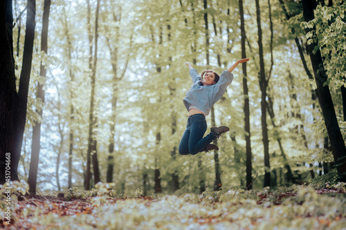 Cheerful Woman full of Joy Jumping in a Forest