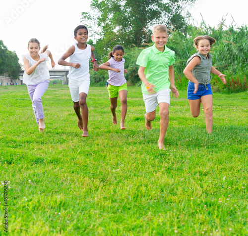 Group of laughing children having fun together outdoors running