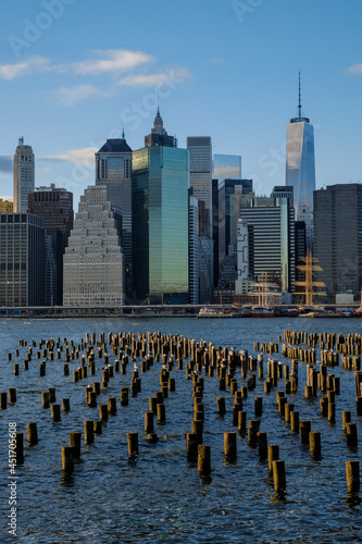 Old Wooden Pilings on the East River reflect the sunset as the lower New York City Manhattan Financial district lights begin to turn on © Jorge Moro