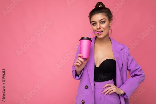 Photo of sexy attractive young happy smiling brunette woman wearing everyday stylish clothes isolated over colourful background wall holding paper cup for cutout drinking tea looking at camera