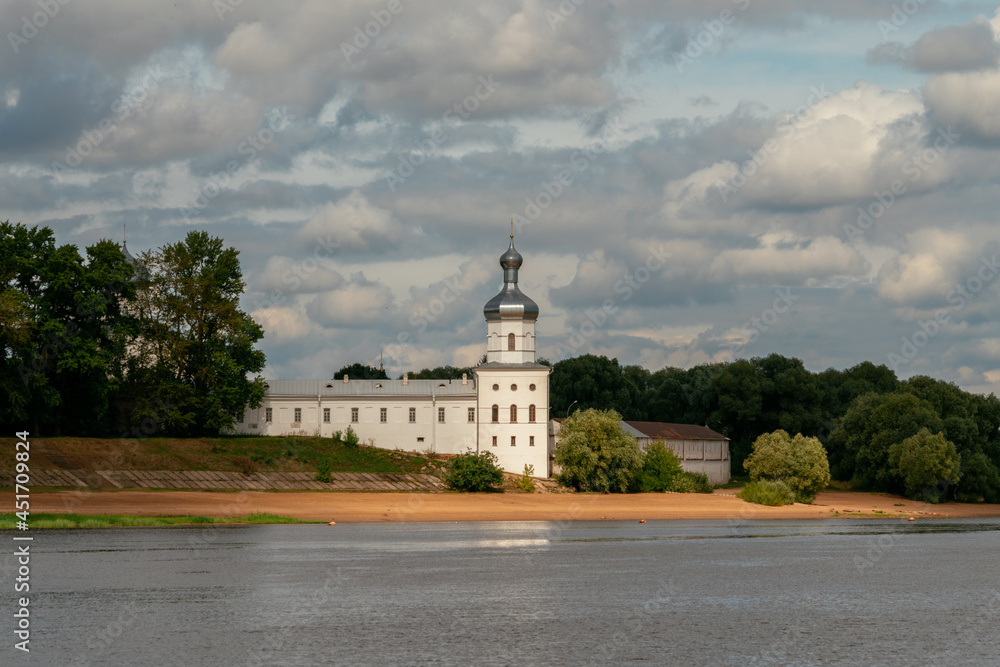 View of the wall of the St. George (Yuriev) Monastery and the Mikhailovsky Tower from the Volkhov River on a sunny summer day with cumulus clouds, Veliky Novgorod, Russia