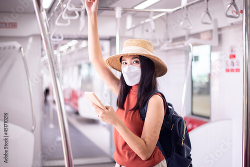 Asian woman wearing face mask and using smartphone on subway train,Safety on public transport,New normal during covid-19 pandemic.