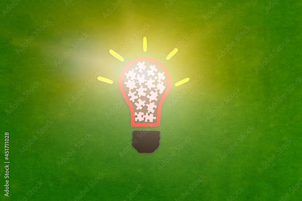 Electric light bulb, puzzle pieces on a green background. The concept of the development of creative ideas.