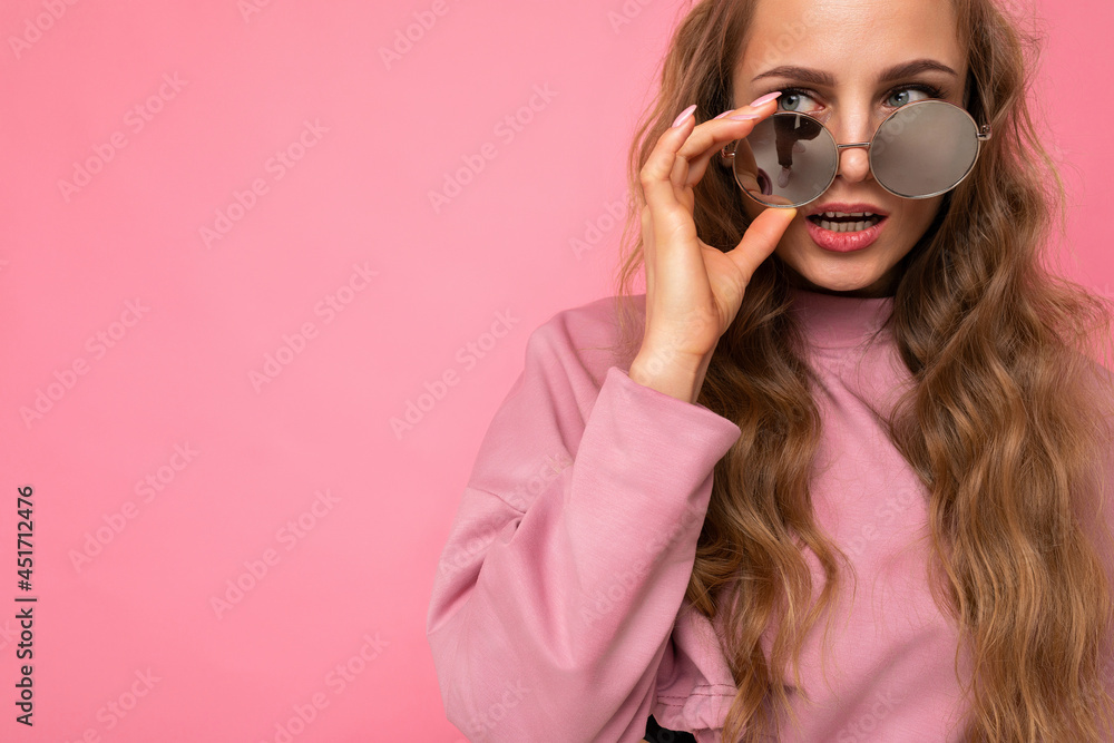 Closeup photo shot of beautiful young dark blonde woman wearing casual clothes and stylish sunglasses isolated over colorful background looking to the side Closeup photo shot of beautiful young dark blonde woman wearing casual clothes and stylish sunglasses isolated over colorful background looking to the side