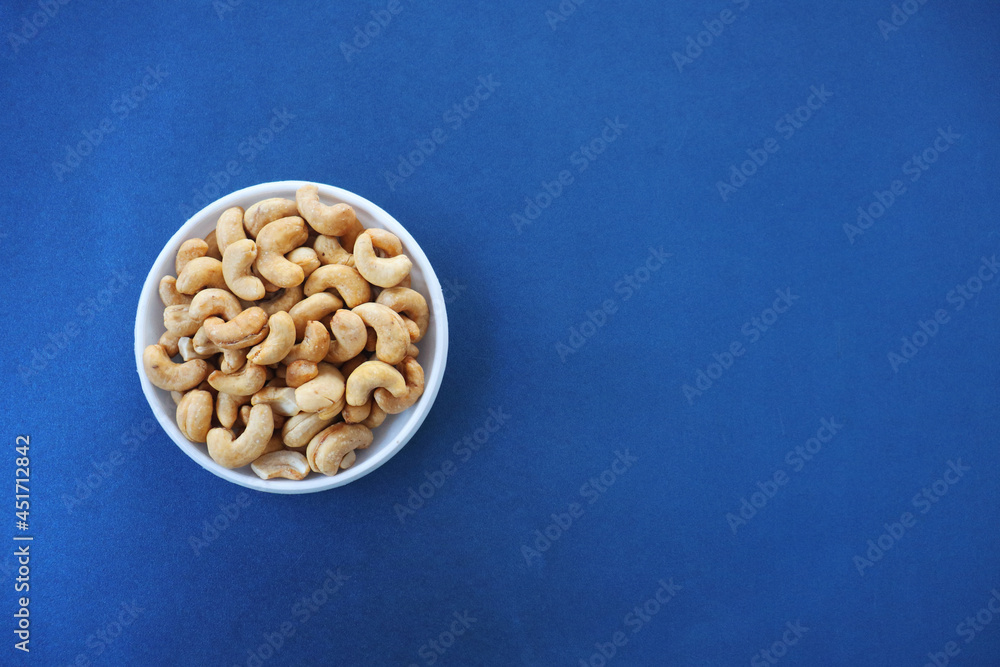 A bowl of cashew nuts on a blue background A bowl of cashew nuts on a blue background