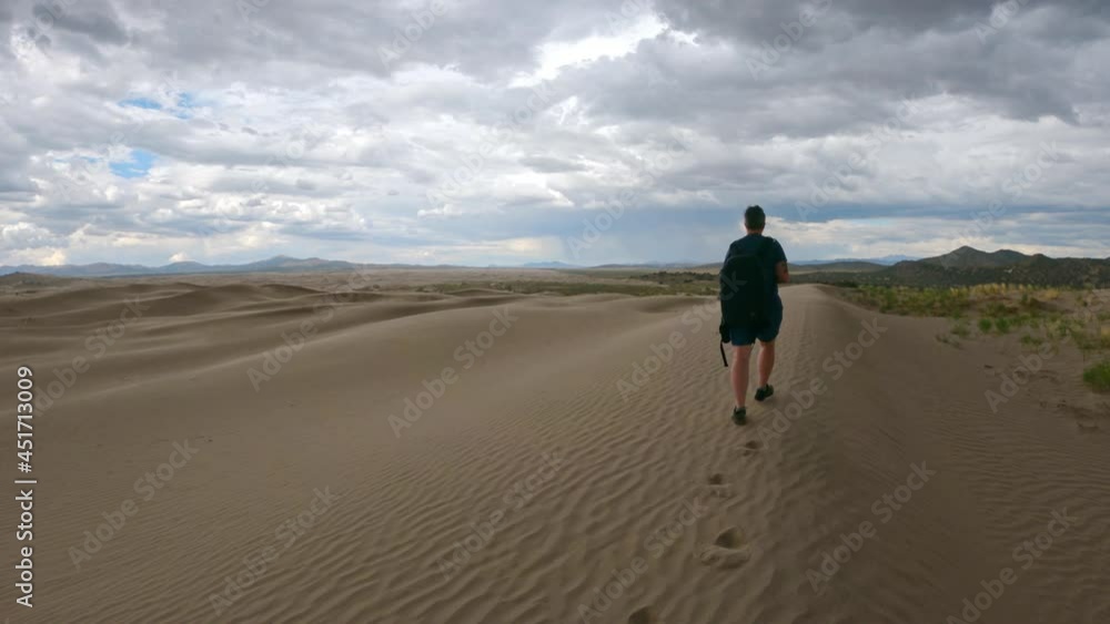 Following woman walking on sand dunes at Little Sahara in Utah on cloudy day in the summer. Following woman walking on sand dunes at Little Sahara in Utah on cloudy day in the summer.