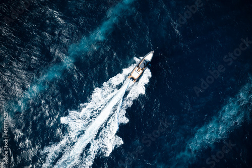 Obraz na płótnie View from above, stunning aerial view of a boat cruising on a blue water creating a wake.Sardinia, Italy. w salonie