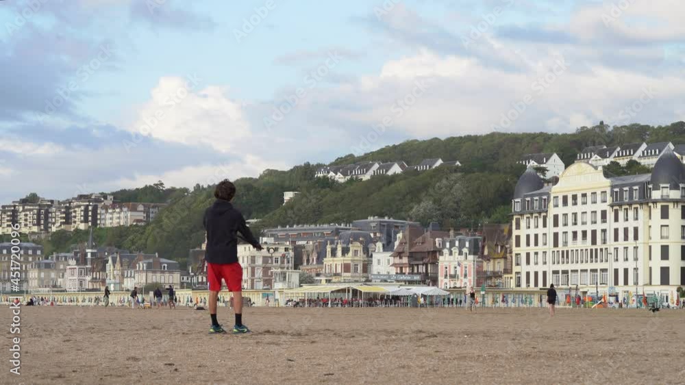 Teenage Boy Standing On The Sand And Flying Kite With Control Bar. wide shot Teenage Boy Standing On The Sand And Flying Kite With Control Bar. wide shot