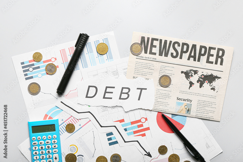 Word DEBT with charts, coins and stationery on light background Word DEBT with charts, coins and stationery on light background