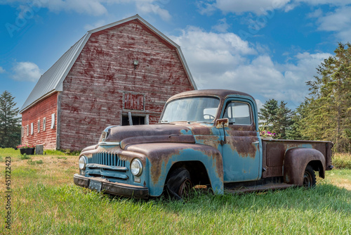 Fotografia Vintage red barn with abandoned truck in a farmyard on the prairies in Saskatche