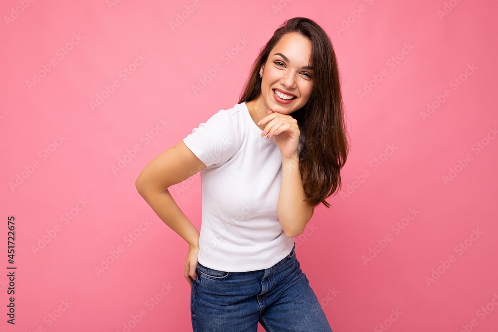 Photo portrait of young beautiful smiling hipster brunette woman in white t-shirt with mockup. Sexy carefree female person posing isolated near pink wall with empty space in studio. Positive model Photo portrait of young beautiful smiling hipster brunette woman in white t-shirt with mockup. Sexy carefree female person posing isolated near pink wall with empty space in studio. Positive model