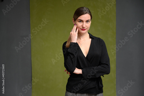 Cute female manager posing with a smile while standing on a dark green background.