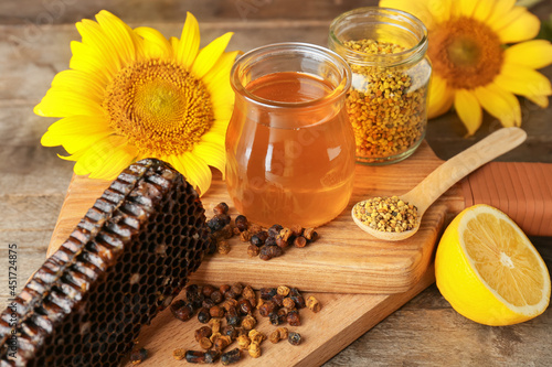 Different bee products with lemon on wooden background photo