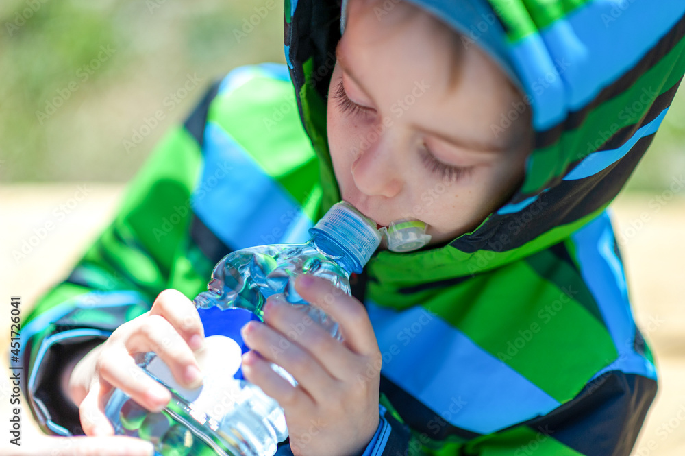 Water for children. A child boy drinks clean fresh healthy water from a ...