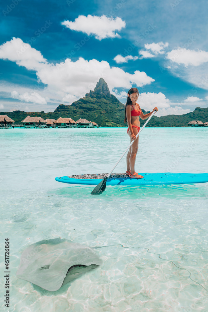 SUP Stand-up paddle board woman wwimming with stingrays tourist tour activity happy Asian woman on Bora Bora island beach at Tahiti overwater bungalow hotel, holiday travel vacation. - obrazy, fototapety, plakaty 