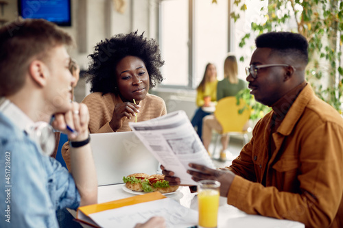 Group of college students learn together during lunch break in cafeteria.