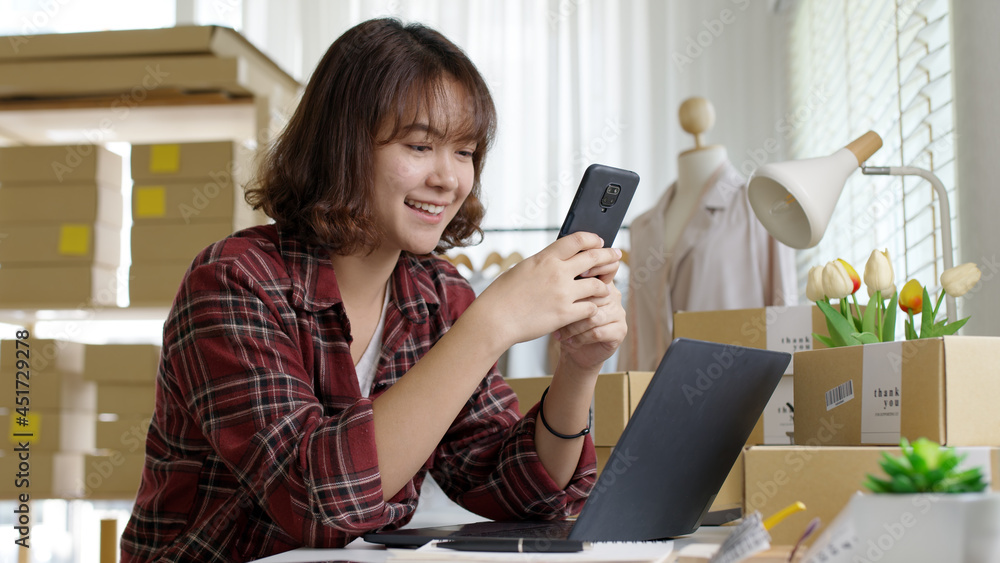 Young asia seller woman happy work on laptop busy cellphone call chat to customer at home office desk use digital tablet computer in SME online store social e-commerce sale page service web support. Young asia seller woman happy work on laptop busy cellphone call chat to customer at home office desk use digital tablet computer in SME online store social e-commerce sale page service web support.