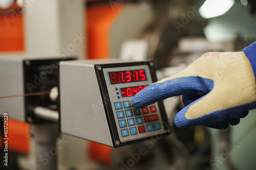 Worker operating a machine in a factory pushing a button