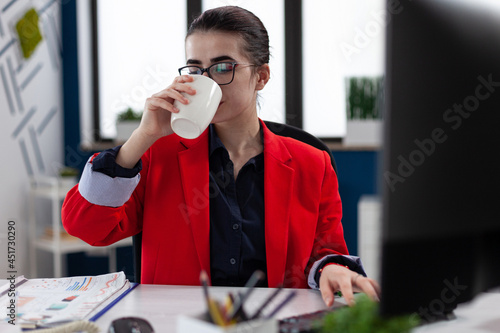 Businesswoman taking a sip of coffe working in corporate office workplace , making financial analysis expertise. succesful Executive manager taking a dose of caffeine. photo