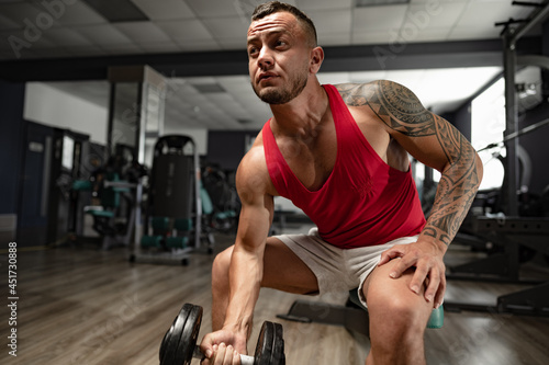 Portrait of man bodybuilder in red shirt in gym