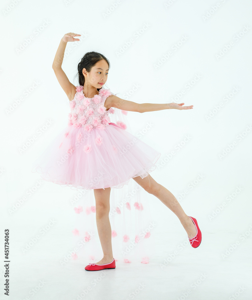 Naklejka premium Isolated full body studio shot of little cute pretty Asian ballerina kid wears pink beautiful roses flowers ballet dress and red shoes smiling posing dancing happily in front of white background