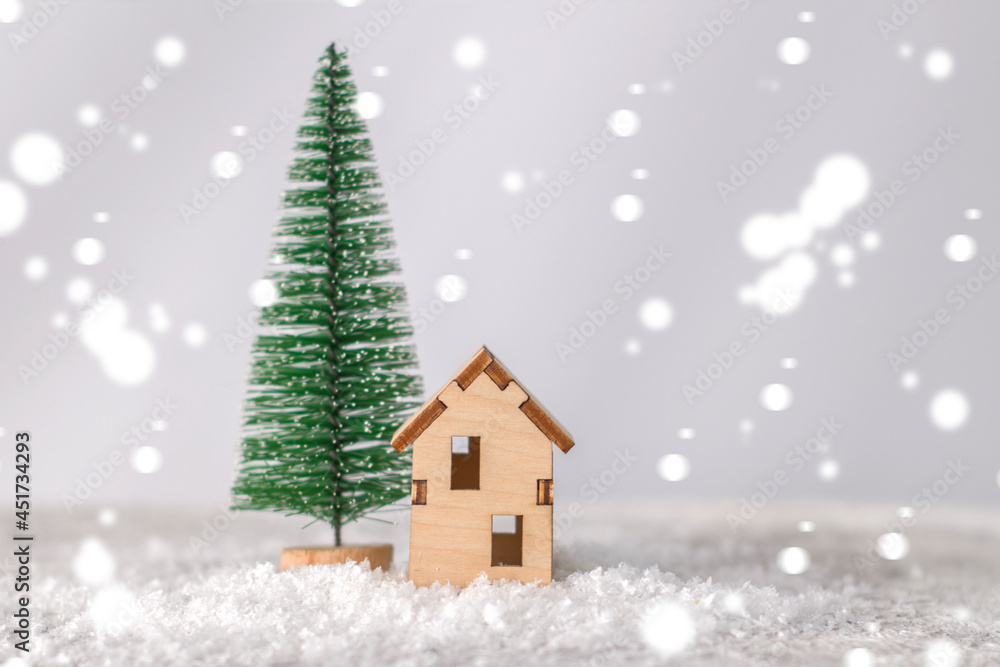 Model of a wooden house near a miniature Christmas tree